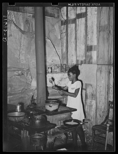 Negro girl attending to food and stove in corner of kitchen, once a room in the old Trepagnier plantation house. Norco, Louisiana