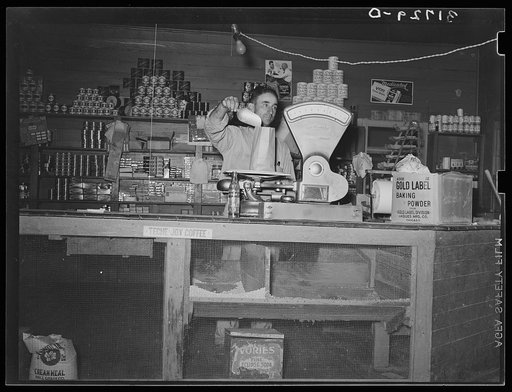 Proprietor of small grocery store weighing dried beans. Near New Iberia, Louisiana. This small grocery store was the center of the social life of the community