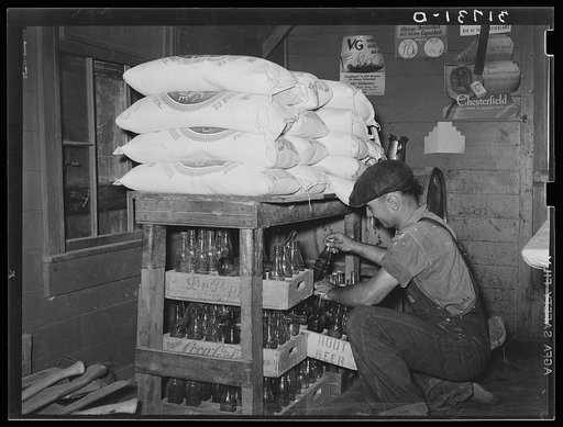 Corner of grocery store with man taking bottled drinks from supplies to fill ice box. Near New Iberia, Louisiana