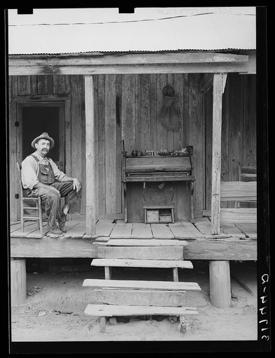 W.E. Smith, farmer near Morganza, Louisiana, sitting on the front porch of his home