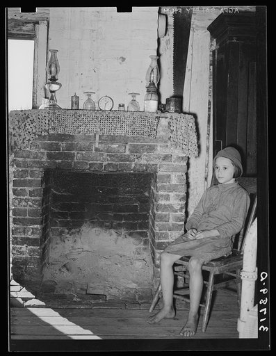 Daughter of Cajun day laborers sitting in front of fireplace in home near New Iberia, Louisiana