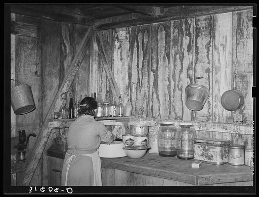 Mrs. M. LaBlanc straightening articles in corner of kitchen in present home. Note the waterstained walls caused by leaking roof. Morganza, Louisiana
