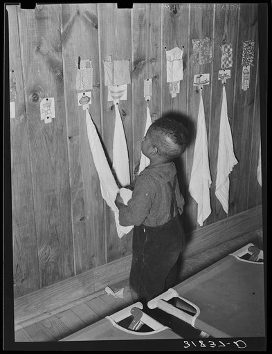 Negro child wiping hands after washing. Note toothbrush and comb for every child. Lakeview nursery school. Arkansas