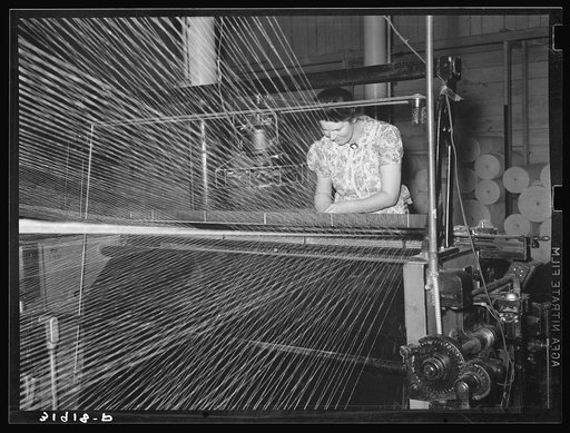 Operator of winding machine in Laurel Cotton Mill repairing break in thread. Laurel, Mississippi