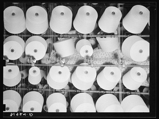 Spools of cotton thread with woman repairing break. Laurel cotton mill, Laurel, Mississippi