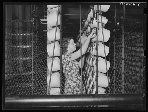 Girl tending spools of cotton in winding process. Laurel mills, Laurel, Mississippi