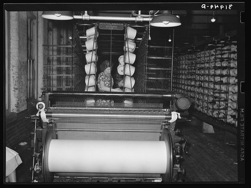 Girl tending spools of cotton in winding process. Laurel, Mississippi