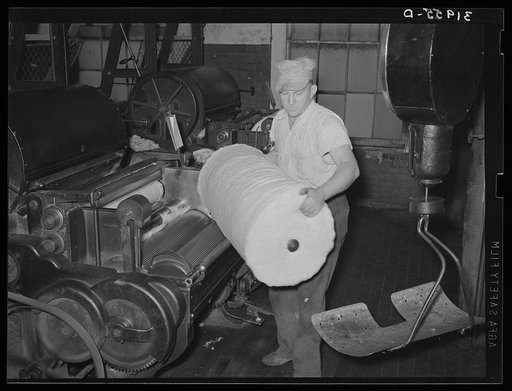 Operator removing bat of cotton from machine. First step of cleaning cotton of trash. Laurel cotton mills, Laurel, Mississippi