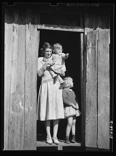 Mrs. Ed Bagget with two children in doorway of sharecropper cabin near Laurel, Mississippi