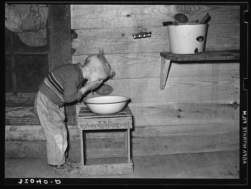 Son of sharecropper washing face. Near Pace, Mississippi. Background, Sunflower Plantation, Mississippi