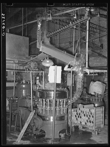 Cans are fed by gravity to a sterilizer and they are then filled in a rotary machine at the grapefruit juice canning plant. Weslaco, Texas