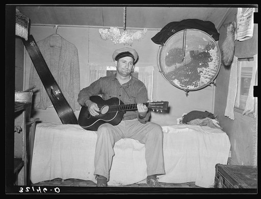 White migrant playing guitar in trailer home. Weslaco, Texas