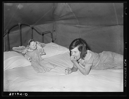 Child migrant with doll in tent home. Harlingen, Texas