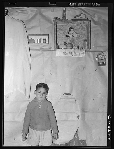 Mexican boy living in corral, Robstown, Texas. Notice the crude wall papering