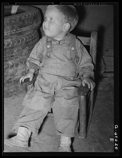 Untitled photo, possibly related to: Child of white migrant auto wrecker sitting next to tires in corner of tent home. Nueces Bay, Corpus Christi, Texas
