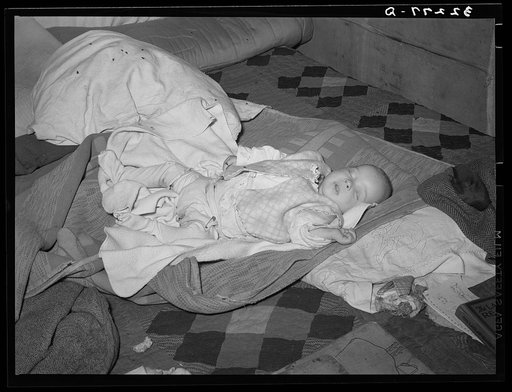 Baby of white migrant auto wrecker living in shantytown on Nueces Bay. Corpus Christi, Texas