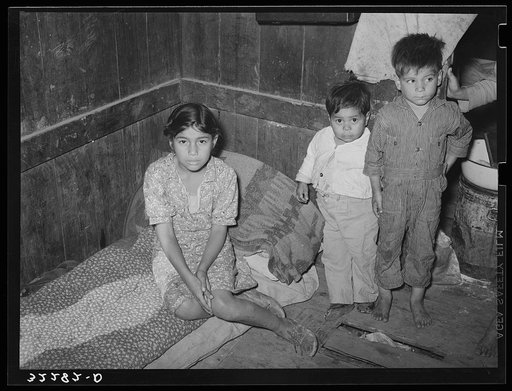 Corner of room in corral. Entire families of six and seven persons live in one small room. Notice roll of bed clothing and condition of floors.  Robstown, Texas (Mexican family)