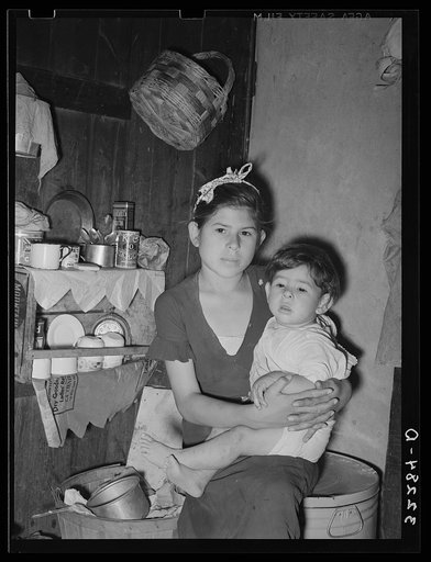 Mexican girl with baby brother in corner of room in which the entire family lives. Robstown, Texas