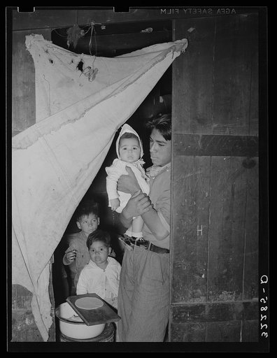 Mexican worker with children in doorway connecting two rooms of corral. Robstown, Texas