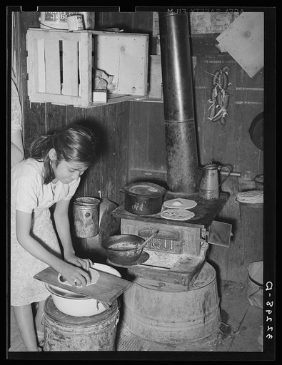 Mexican girl living in corral making tortillas. Tortillas can be seen baking on the stove. Robstown, Texas
