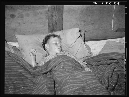 A sick child sleeping in trailer home of his father near Sebastian, Texas. This family was originally from Iowa but had been in Texas doing migrant work the the last several years. They had found no work in the valley