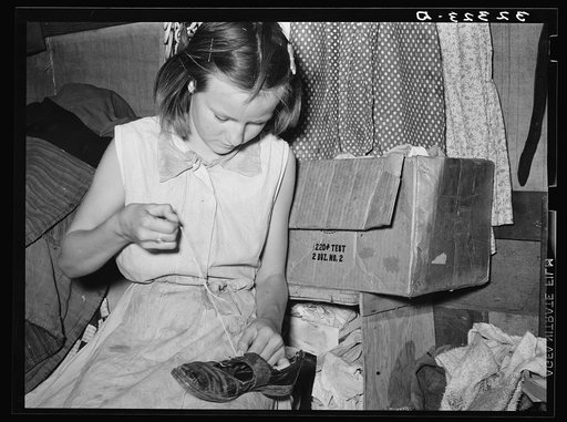 Daughter of white migrants repairing shoes with cotton thread. Sebastian, Texas