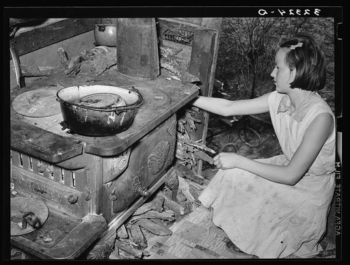 Daughter of white migrants reaching for stick of wood. Sebastian, Texas