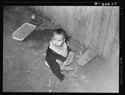 Mexican child playing outside of corral in dirt. Robstown, Texas