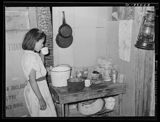 Mexican girl drinking a cup of water in the kitchen of her home in San Antonio, Texas