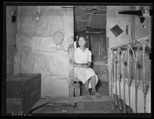Mexican girl sitting in doorway between living room and bedroom. San Antonio, Texas