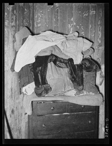Clothing piled atop bureau in Mexican house in San Antonio, Texas. There is lack of closet space in the houses of Mexicans