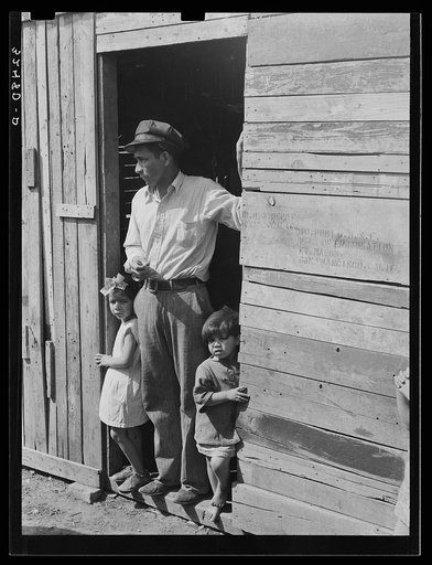 Untitled photo, possibly related to: Mexican father and children in doorway of their home made of scrap lumber. San Antonio, Texas