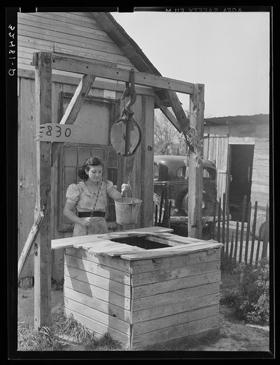Mexican girl drawing water from well. City water is not supplied to all sections of the city. San Antonio, Texas