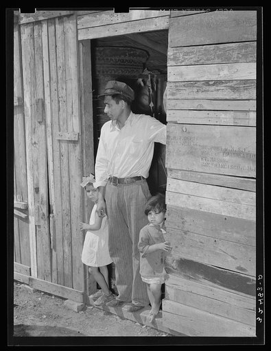 Mexican father and children in doorway of their home made of scrap lumber. San Antonio, Texas