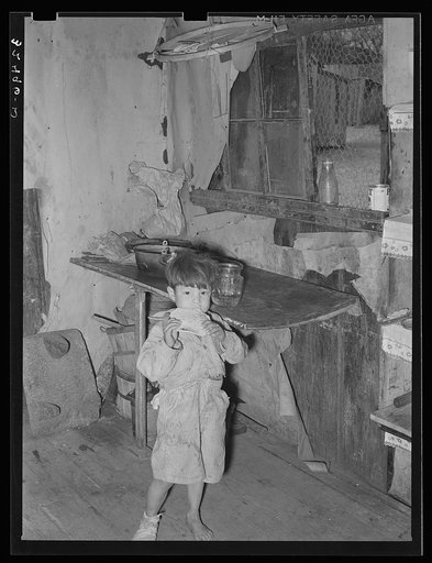 Mexican child eating tortilla in corner of kitchen. San Antonio, Texas