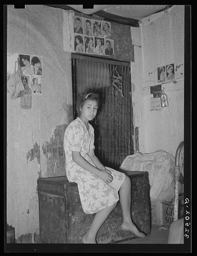 Mexican girl sitting in front of bedspring which formed partition between the family's living quarters and those of a man boarder. San Antonio, Texas, corral