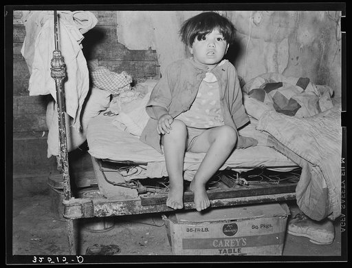 Mexican child sitting on bed. San Antonio, Texas
