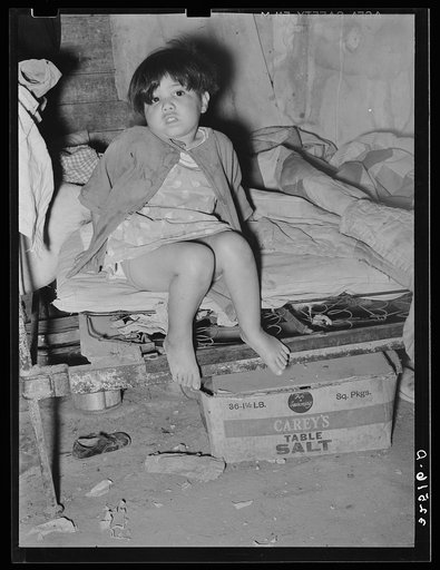 Mexican child sitting on bed. San Antonio, Texas