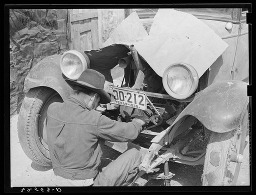 Mexican repairing automobile. San Antonio, Texas. Notice the worn-out tires