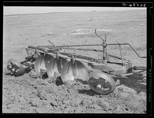 Disk plow drawn by tractor breaking virgin sod. El Indio, Texas