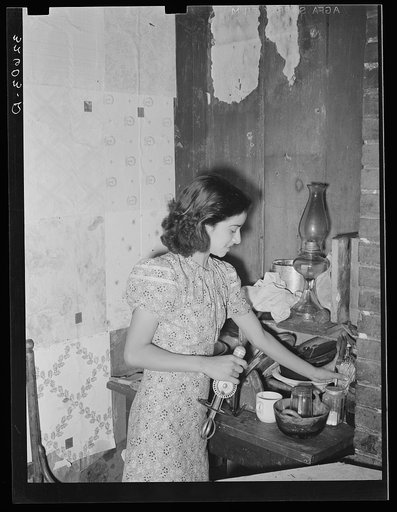 Mexican girl straightening corner of her kitchen. San Antonio, Texas