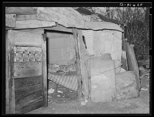 Bedroom of house made of tin and scrap wood in Mexican section of San Antonio, Texas