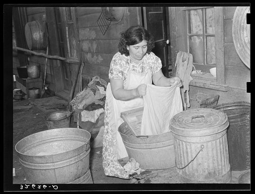 Mexican woman washing in front of house in corral. Mexican section, San Antonio, Texas