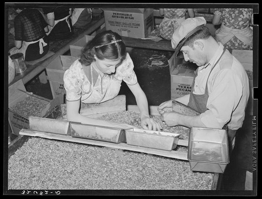 Owner of pecan shelling plant with girl who is separating the whole meats from the broken ones. Union plant. San Antonio, Texas