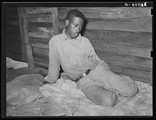 Negro strawberry worker sitting on his bunk in bunkhouse. Hammond, Louisiana