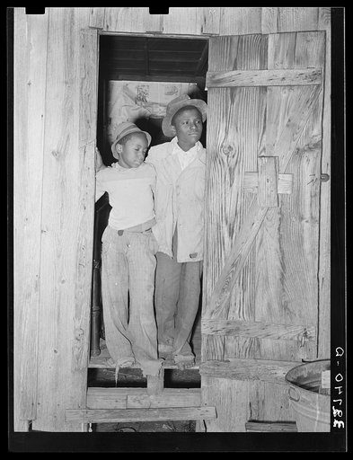 Two young Negro strawberry pickers standing in doorway of their temporary house near Independence, Louisiana