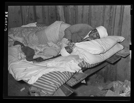 Negro mother and baby in bed in the house furnished them while working in the strawberry fields near Independence, Louisiana