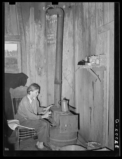 White migrant berry picker warming her hands over a makeshift stove constructed by her husband. This couple was from Meridian, Mississippi, where they had been tenant farmers. They have picked berries from Illinois down. Picture taken near Hammond, Louisiana