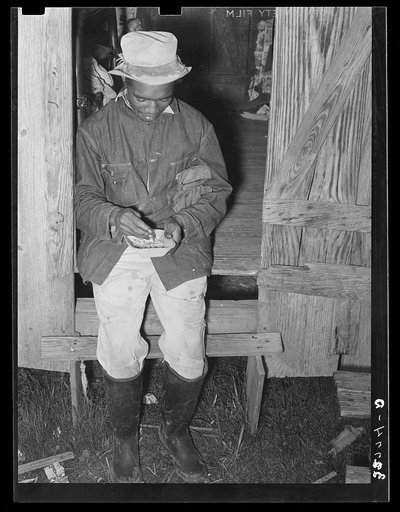 Negro strawberry worker examining watermelon seeds which he was planning to plant. Near Independence, Louisiana