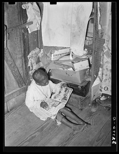 Negro boy looking at mailorder catalogue. This house is one of those provided for migrant strawberry pickers. Near Independence, Louisiana